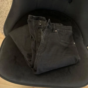 Svarta skinny jeans med hög midja - Svarta jeans med skinny fit och hög midja. Med dragkedja och knapp framtill. Jeansen är i stretchigt denimtyg som sitter tajt längs benen. Perfekta för en vardaglig outfit.
