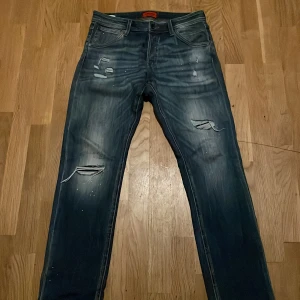 Jack & Jones Slim Glenn jeans blå 32/32 - Snygga blå jeans från Jack & Jones, modell Slim Glenn. De har slitna detaljer och trasiga partier framtill för en cool, avslappnad look. Klassisk femficksmodell med normal midja och smal passform. Tillverkade i jeansmaterial med lätt tvättad effekt.