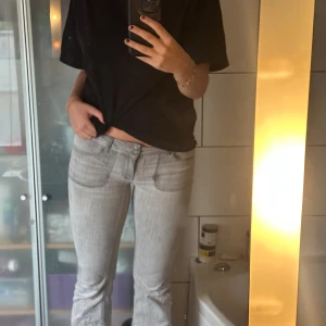 Ljusgrå bootcut jeans med fickor - Snygga ljusgrå jeans med bootcut passform och stora framfickor. Baktill finns fickor med lock och knapp. Jeansen har låg midja och är tillverkade i ett klassiskt denimtyg. Perfekta för dig som gillar en retroinspirerad look. Dom är från Nelly och är i storlek S/M