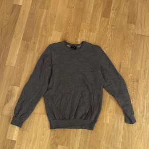 Mörkgrå stickad tröja från Sand S - Mörkgrå stickad tröja från Sand Copenhagen med rund halsringning och ribbade muddar. Enkel och stilren design som passar perfekt till jeans eller chinos. Mjuk och skön känsla tack vare det stickade materialet. Storlek S, säljer då den inte passar mig längre 