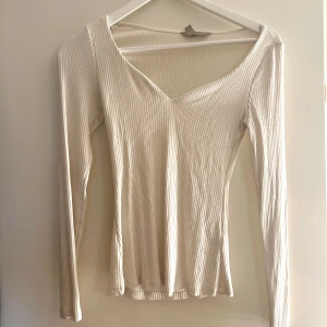 Ribbad vit  långärmad topp - Säljer en vit ribbad topp med lång ärm och snygg v-ringning. Toppen är figurnära. Bra skick!