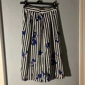 Randiga och blommiga byxor - Mörkblå och vit randiga trekvartsbyxor med blårosa blommor. Från Carin Wester. Högmidjade. Storlek 36. Gott skick, bara använde ett par gånger