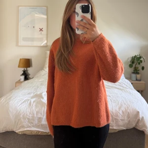 Orange stickad tröja - Mysig orange stickad tröja med rund hals och lång ärm. Tröjan har en loose passform och är perfekt för lager-på-lager. Enkel och stilren design som passar till jeans eller leggings.