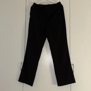 Svarta kostymbyxor med raka ben - Stilrena svarta kostymbyxor med raka ben och klassisk passform. Byxorna har hällor för bälte och diskreta fickor bak. Perfekta för en clean och dressad look. Materialet känns mjukt och följsamt.