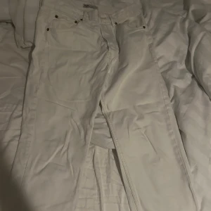 Vita raka jeans från Zara - Säljer ett par vita jeans från Zara med klassisk femficksdesign och raka ben. Byxorna har bälteshällor, metallnitar och är tillverkade i bomull. Perfekta för dig som vill ha en clean och fräsch look.