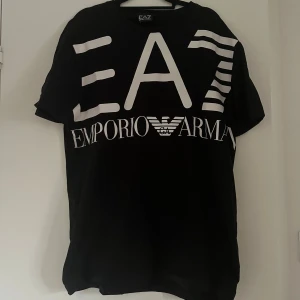 Svart EA7 Emporio Armani t-shirt - Svart t-shirt från EA7 Emporio Armani med stor vit logga och tryck framtill. Klassisk rund hals och korta ärmar. 