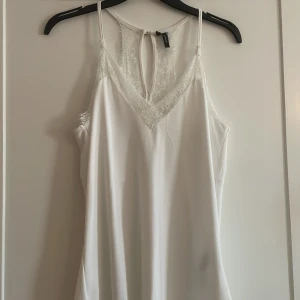 Vit spetsdetaljerad linnetopp Vero Moda - Supersöt vit linnetopp från Vero Moda med tunna axelband och v-ringning. 