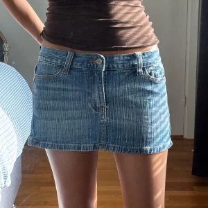 Blå jeanskjol i kort modell - Säljer en snygg blå jeanskjol i kort modell med klassiska fickor fram och bak, bälteshällor och knappstängning. Kjolen har en rak passform och är tillverkad i denim med en ljus tvätt. Från brandy Melville. Passar XS-S