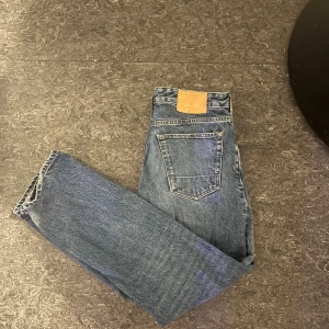 Junk de Luxe Jeans - Snygga blå jeans från Junk de Luxe i klassisk femficksmodell med coola detaljer som grön kronbroderi på myntfickan och brunt läderpatch bak. Jeansen har normal passform och raka ben, tillverkade i slitstarkt denim med kontrastsömmar.