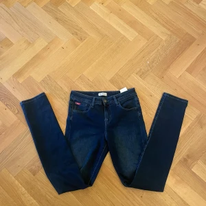 Mörkblå slim jeans från Lee - Snygga mörkblå jeans från Lee Cooper med klassisk femficksdesign och diskret broderad bakficka. Jeansen har slim passform och är tillverkade i stretchigt denim för en bekväm känsla. Perfekta till sneakers eller boots. Ungefär W29 L30