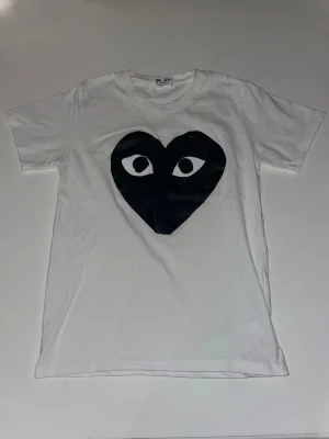 Comme des Garçons Play t-shirt | Vit - Säljer en vit t-shirt från Comme des Garçons Play med det ikoniska svarta hjärtat med ögon tryckt på bröstet. | Storlek M i tröjan, men sitter som en S | Skick 7/10, loggan har på vissa ställen tappat färg pågrund av att mamma tvättade den i tvättmaskinen i för höga grader Om du har några funderingar kring t-shirten eller priset är de bara att höra av sig i pm | MVH William🙌
