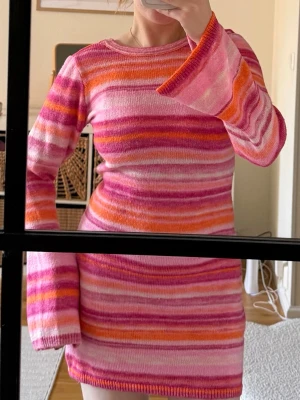 Randig stickad kortklänning  - Säljer en stickad kortklänning med färgglada ränder i rosa, orange och vit🧡🩷🤍🧡🩷🤍