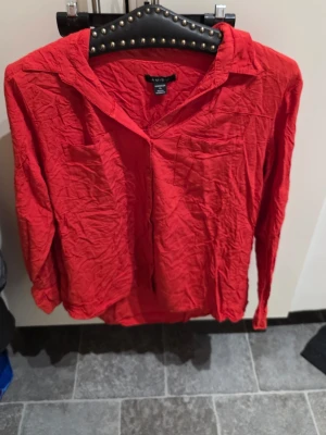 Röd skjorta från Amisu i storlek XL - Säljer en röd skjorta från Amisu i storlek XL. Skjortan har klassisk krage, lång ärm och en bröstficka. Materialet är lätt och skönt, perfekt för dig som gillar en enkel men färgstark look. Passar till många olika stilar!
