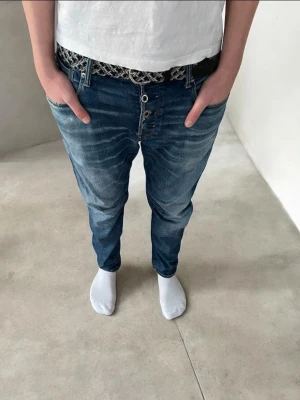 Blå jeans från g-star raw - Säljer ett par blå jeans, snygga slitningar. Jeansen har flera knappar i gylfen och stora bakfickor. Perfekta för en avslappnad stil och passar till det mesta. Bältet på bilden ingår ej.