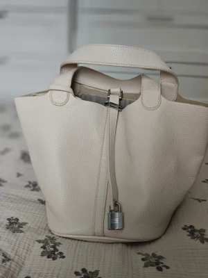 Beige bucket bag i läder - Hobo väska, med extra band som ej passar exakt i färgen, men fungerar. Vegansk läder men fin kvalite. Använd endast en gång. Inget märke på den.