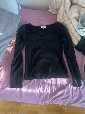 Svart ribbad topp från &other stories - Svart långärmad topp & other Storys med ribbad struktur och snygg sweetheart-urringning. Perfekt att styla med jeans eller kjol för en trendig look.