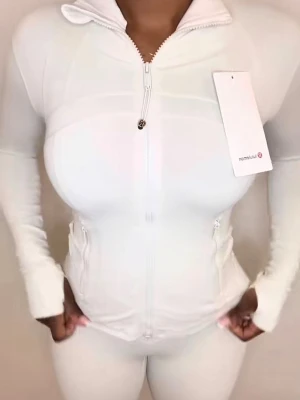 Creme vit zip hoodie från Lululemon - Supersnygg creme vit hoodie från Lululemon med dragkedja framtill och hög krage. Tillverkad i mjukt och stretchigt syntetmaterial, perfekt för träning. Slim fit med långa ärmar och tumhål. Två fickor med dragkedja på sidorna för smart förvaring. Endast använd o tvättad en gång.