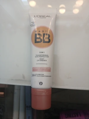 L'Oréal Magic BB Cream Medium - L'Oréal Paris Magic BB Cream i nyansen Medium är en 5-i-1 foundation med vitamincomplex (B5 + E) som jämnar ut hudtonen och ger 24h återfuktning. Tuben är vit med persikofärgat lock och detaljer, och innehåller en lätt krämig formula.