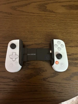 Backbone One mobil handkontroll vit - Backbone One är en vit handkontroll för mobilspel. Den har två analoga spakar, styrkors, knappar och triggers. Kontrollen är utdragbar och passar de flesta smartphones. Perfekt för gaming på språng och enkel att koppla in.