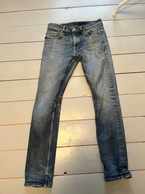 Tiger of Sweden blå jeans straight fit - Snygga blå jeans från Tiger of Sweden i storlek 30/32 med klassisk femficksdesign och raka ben. Jeansen har en mörkblå tvätt med lätt slitning och bruna detaljer på midjan. Passar dig som gillar stilrena och tidlösa jeans med normal passform.