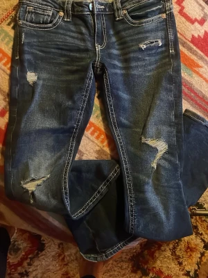 Blå jeans från Gina Tricot 14+ - Snygga blå jeans från Gina Tricot. Bakfickan har en broderad detalj. Jeansen är i bootcut modell med låg midja.