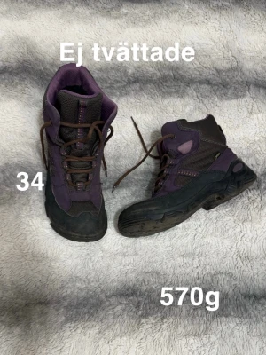 Lila och svarta kängor strl 34 - Säljer ett par robusta kängor i lila och svart med snörning och grov sula. Skorna har förstärkta partier för extra hållbarhet. Perfekt för utomhusaktiviteter och äventyr. 🌸Fint använt skick. Ej tvättade. Storlek 34 