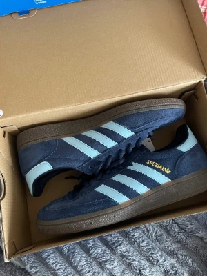 Adidas Handball Spezial marinblå sneakers - Adidas Handball Spezial sneakers i marinblå mocka med ljusblå ränder och detaljer. Helt nya i perfekt skick. Storlek 42 2/3. Skriv för fler bilder eller mer info!