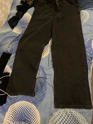 Svarta jeansbyxor i straight fit - Svarta jeansbyxor med klassisk femficksdesign och rak passform. Byxorna har knappgylf och är tillverkade i slitstarkt jeanstyg. Perfekt för dig som gillar en enkel och clean look. Storlek 29/30.