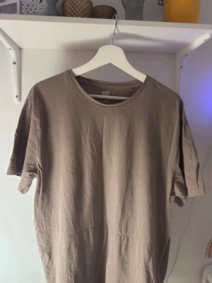 Beige t-shirt från 157 - Säljer en enkel och stilren beige t-shirt från 157. T-shirten har rund hals och korta ärmar, perfekt för dig som gillar en clean och chill look. Materialet är mjuk bomull som känns skönt mot huden. Passar dig som vill ha en basic tee i garderoben.