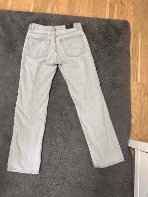 Ljusgråa raka jeans - Säljer ett par klassiska ljusgråa jeans med raka ben och femficksmodell. Jeansen har normal passform och är tillverkade i slitstarkt bomullsjeansmaterial. Perfekta för dig som gillar en tidlös och clean look. Finns nån grå fläck på jeansen men det är inget som man riktigt tänker på när man har på sig dom.