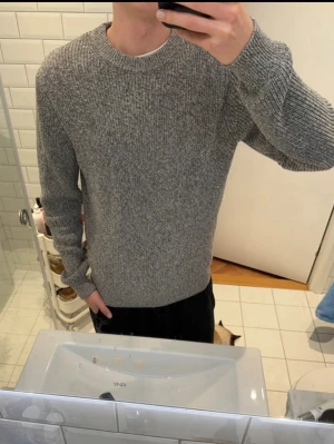 Massimo dutti - Säljer en grå stickad tröja med rund hals och långärmade ribbade muddar. Perfekt för kyliga dagar och enkel att matcha med jeans eller svarta byxor. Tröjan har en klassisk och avslappnad passform som passar de flesta stilar. Byten
