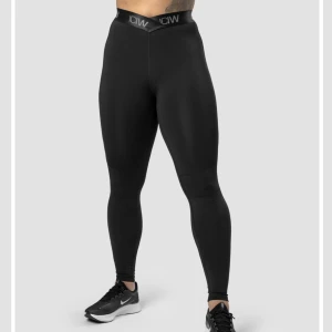 Ultimate Training V-Shape Tights från Icaniwill - Säljer ett par svarta leggings från ICANIWILL med bred elastisk midja och logga. Materialet är stretchigt med 78% återvunnen polyester och 22% spandex, vilket gör dem riktigt sköna och följsamma. Perfekta för träning eller chill.  silikonremsor på insidan av midjan för extra grepp. Nypris 799kr 