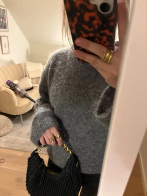 Svart handväska med kedjehandtag - Säljer en svart handväska med flätad look och chunky guldfärgad kedja som handtag. Väskan har dragkedja upptill och är tillverkad i ett material som liknar skinn. Perfekt accessoar för att lyfta din outfit. Köpte den på hm i Spanien!
