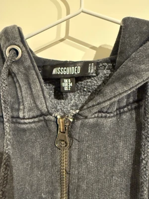 Grå/svart huvtröja med acidwash  - Tröjan har dragkedja och luva. Färgen är menad att vara ”fläckig” :)