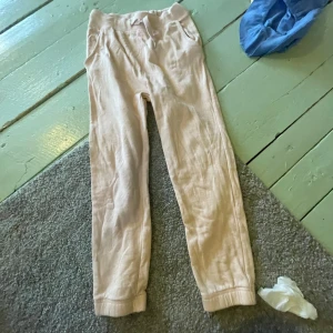 Ljusrosa mjukisbyxor med snörning - Ljusrosa mjukisbyxor med resår och snörning i midjan. Byxorna har ribbade muddar vid bensluten och sidofickor. Perfekta för en chill och avslappnad stil. Tillverkade i mjukt material som känns skönt mot huden.  