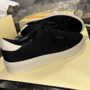 Axel Arigato (Oanvända) - Säljer ett par helt nya (oanvända) Axel Arigato skor i Suede.  Skorna heter ”clean court suede” och finns inte att köpa nya nånstans. Box, pappers ilägg, plastpåse/skyddsplast, stickers, skopåse/dustbag är allt original och säljs med skorna