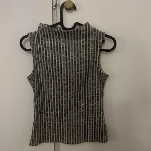 Randig ärmlös topp från Lindex XS - Säljer en svartvit ärmlös topp från Lindex i storlek XS. Toppen har ett coolt vertikalt randigt mönster och en något högre halsringning. Perfekt att styla med jeans eller kjol för en trendig look.