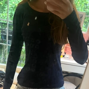 Mörkblå långärmad tröja Polo Ralph Lauren - Snygg mörkblå långärmad tröja från Polo Ralph Lauren med klassisk rund halsringning och broderad logga på bröstet. Tröjan är i mjuk bomull och har en slim passform som sitter riktigt bra. Perfekt till jeans eller kjol för en clean look.