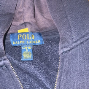 Mörkblå hoodie från Polo Ralph Lauren - Mörkblå hoodie från Polo Ralph Lauren med dragkedja och huva. Klassisk röd broderad logga på bröstet och känguruficka framtill. Mjuk insida och stilren look, perfekt för chill dagar. Passar dig som gillar enkel och tidlös style. Pris kan diskuteras vid snabb affär hör av dig vid frågor ❗️