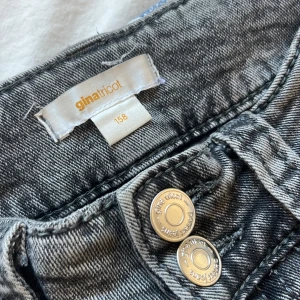 Grå jeans från Gina Tricot, stl 158 - Snygga grå jeans från Gina Tricot i storlek 158. Klassisk femficksmodell med bootcut ben silverfärgade knappar framtill. Jeansen är lowwaist och är i storlek 158. Pris går att diskutera💕