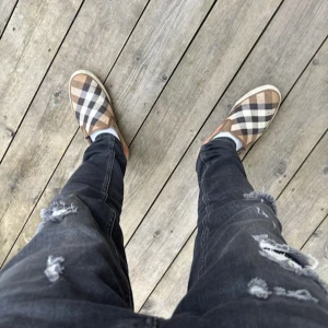 Burberry skor  - Säljer ett par snygga slip-on sneakers från burberry. Det finns lite defekter i dom men det är inget man känner när man har på sig dom, det är storlek 42, skriv vid intresse och frågor. 