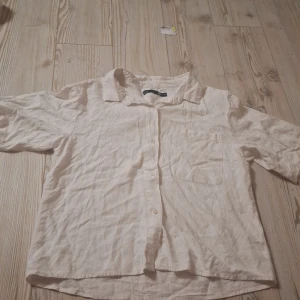 Vit linneskjorta - Luftig vit skjorta från 157 i storlek XS. Skjortan är tillverkad i linne, har korta ärmar, klassisk krage, knäppning framtill och en bröstficka. Perfekt för varma dagar och enkel att matcha med jeans eller shorts. Den är dock inte stryckt så det får man göra när den kommer.