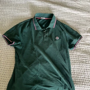Moncler piké - Säljer denna snygga Mocker piké i mörk grön härlig färg! Använd fåtal gånger då den inte riktigt passar mig i storleken! Ny pris ligger på cirka 4000kr, mitt pris 900! Priset är ej hugget i sten!