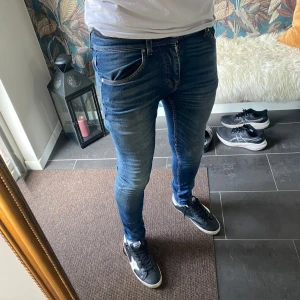 Tiger Of Sweden Jeans - Säljer ett par blå skinny jeans från Tiger Of Sweden modell Evolve. Jeansen har snygga slitningar och tvättade detaljer, klassisk femficksdesign och normal midja. Tillverkade i Italien och passar dig som gillar en tight passform och modern look.