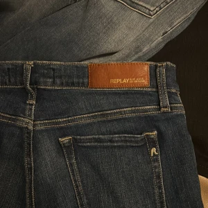 Mörkblå jeans från Replay - Snygga mörkblå jeans från Ralph Lauren med klassisk femficksdesign och läderpatch bak i midjan. Jeansen har raka ben och är tillverkade i mjukt bomullsjeansmaterial. Perfekta för en stilren och avslappnad look.små i storlekarna