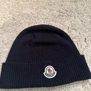 Moncler mössa - En Moncler mössa som är perfekt för de kallare vädren. Den är använd men har knappt några tecken på användning. Skicket 9,5/10 och rekommenderas starkt