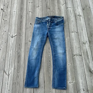 Blå jeans från Jacob Cohën - Snygga blå jeans från Jacob Cohën med klassisk femficksdesign och knäppning framtill. Jeansen har en rak passform och diskret slitning på låren för en cool look. Tillverkade i mjukt denimtyg med detaljerade sömmar och exklusiv etikett bak.