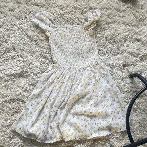 Vit blommig kortklänning från Ellos - Supersöt vit kortklänning från Ellos med små gula blommor och puffiga axelband. Smockad överdel ger en skön passform och kjolen är lätt och luftig. Perfekt för varma dagar och har en riktigt fräsch vibe. Materialet känns mjukt och svalt mot huden. Pris kan diskuteras och skriv för fler bilder eller frågor ❤️