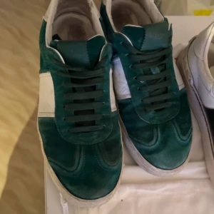 Valentino flycrews sneakers grön/vit - Snygga Valentino Rockrunner sneakers i grön mocka med vita skinnpaneler och klassiska nitar på hälen. Skorna har rund tå, snörning och platt sula. Perfekta för dig som vill sticka ut med en lyxig och sportig look.