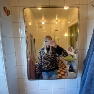 Tiger mönstrad  stickad tröja - Säljer en fluffig stickad tröja med tiger mönster i svart och beige. Tröjan har breda svarta muddar vid ärmslut och nederkant, samt långärmad och loose passform. Perfekt för dig som gillar djurmönster och vill ha en mysig look!🤎🖤